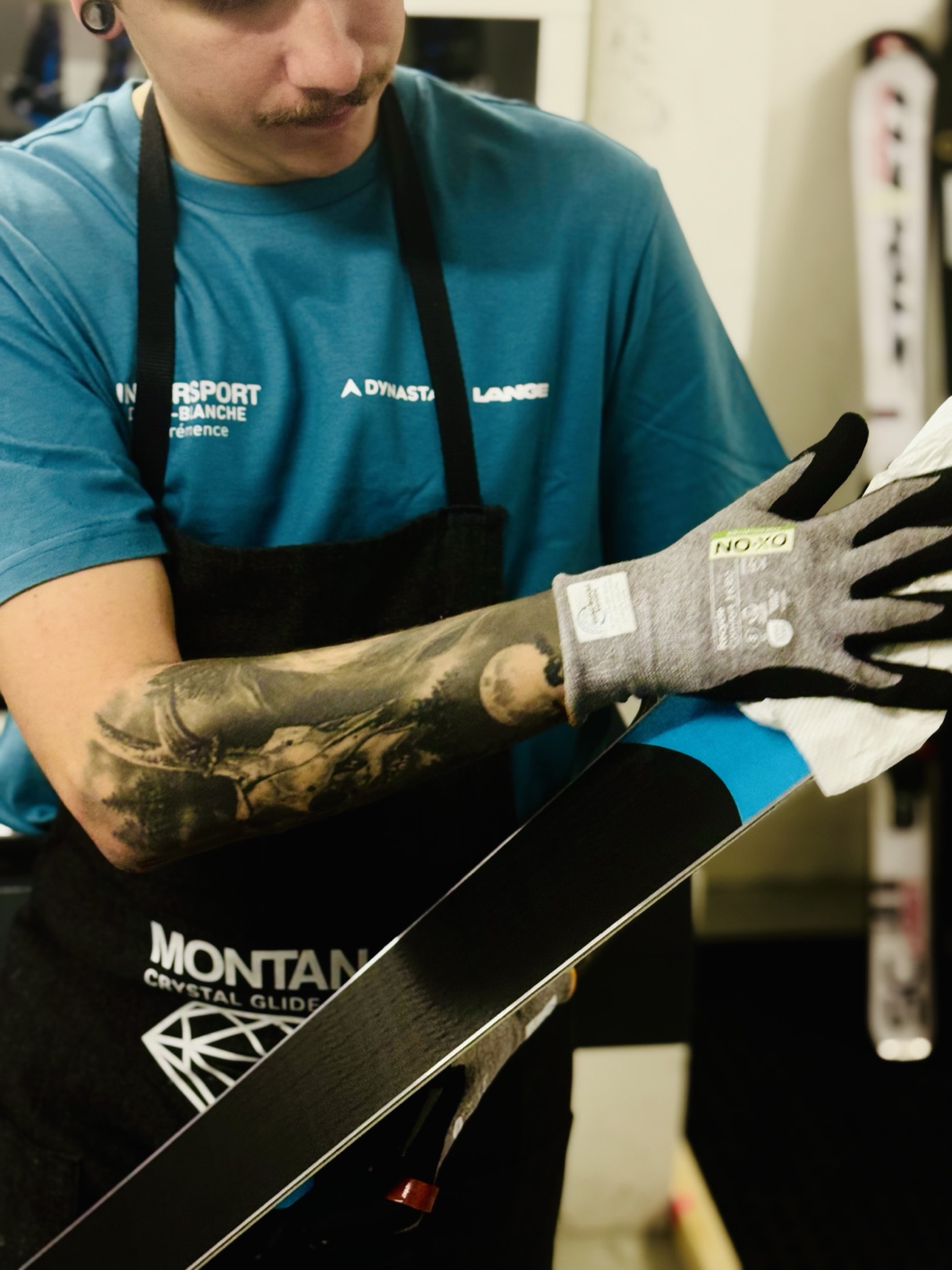 Technicien nettoyant et fartant la carre d'un ski en atelier